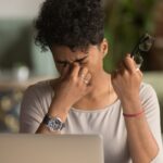A woman experiencing dry eye syndrome at work
