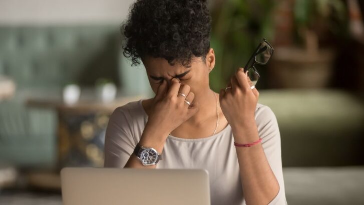 A woman experiencing dry eye syndrome at work